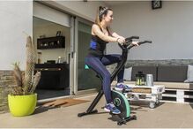 Mulher exercita-se em bicicleta estática em casa para manter a forma