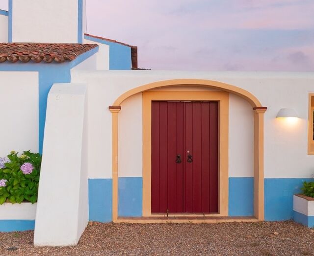 Porta de madeira vermelha em casa alentejana, um refúgio de calma na Páscoa