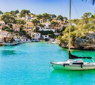 Porto com barcos e casas à beira-mar, destino popular de verão