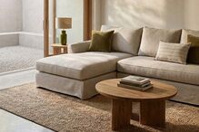 Sala de estar luminosa com sofá, mesa de centro com livros e tapete rústico