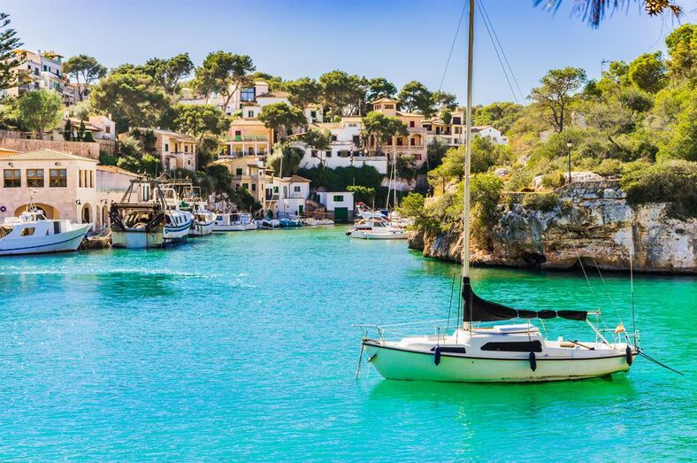 Porto com barcos e casas à beira-mar, destino popular de verão