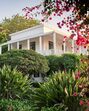 Casa branca com varanda e vegetação exuberante