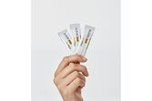 Mão segura 3 ampolas de Heliocare 360º Junior Oral Sticks