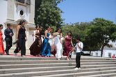 Um grupo de mulheres desce escadas, algumas com vestidos de gala, a caminho de um evento