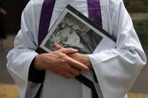 An unidentified priest holds a Bonnie Tyler poster outside St.