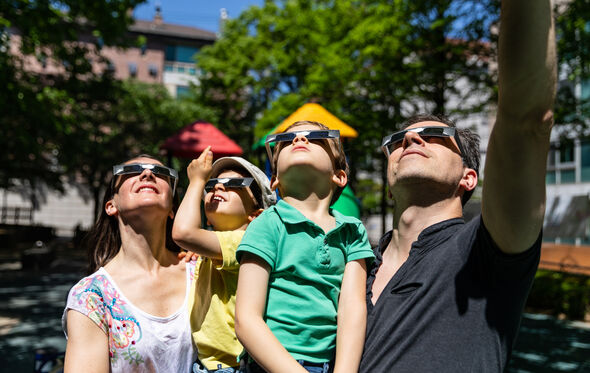 Família com óculos especiais para ver o eclipse do sol