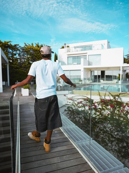 Um homem de costas observa uma mansão moderna com piscina