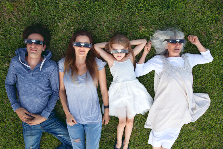 Família deita-se na relva a ver o eclipse com óculos especiais