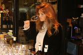 Mulher com cabelo ruivo avalia um copo de vinho branco